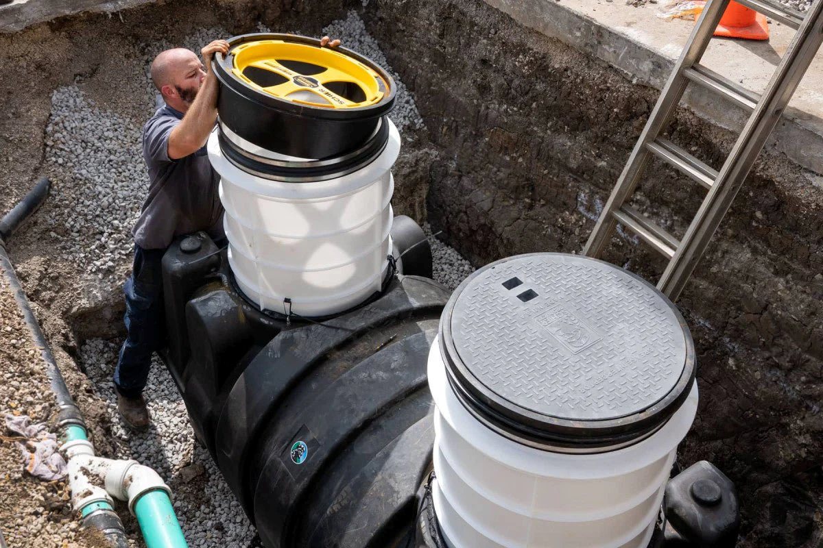 Plumber installing a Schier grease interceptor in an underground excavation site